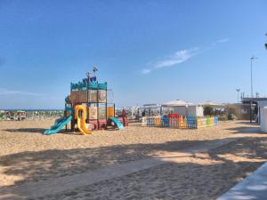 a playground on a beach with the ocean in the background at Maria in Lignano Sabbiadoro