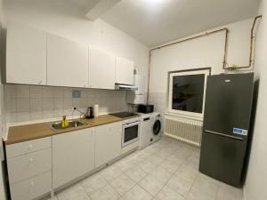 eine Küche mit weißen Schränken und einem schwarzen Kühlschrank in der Unterkunft 3-SZ Monteurwohnung am Hansaring in Neumünster