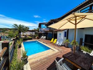 uma casa com piscina e uma mesa com guarda-sol em Pousada Solar de Búzios em Búzios