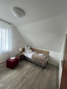 a small bedroom with a bed and a red stool at Schröders Gästehaus in Langstedt