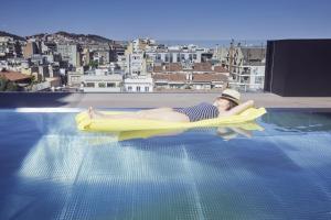 Kobieta leży na tratwie w basenie. w obiekcie The Onsider - Luxury high standing 3 Bedroom Apartment w Barcelonie
