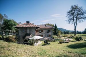 a stone house with a table and chairs in a field at Chalet Maso Pino in Castello Tesino