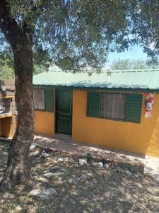 una casa amarilla con una puerta verde y un árbol en Casa de alquiler 2 in 