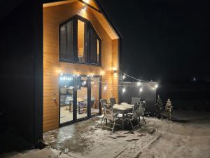 una casa con mesa y sillas por la noche en Domki Diabolina - sauna, jacuzzi, klimatyzacja, kominki en Krajno Pierwsze