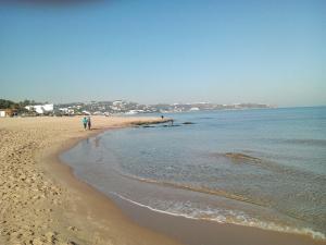 a beach with two people walking on the sand at Dar El Marsa Hotel & Spa in La Marsa