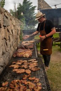 un hombre está cocinando carne en una parrilla en Posada Punta de Piedra en La Cumbre