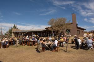 Posada Punta de Piedra في لا كومبر: مجموعة من الناس يجلسون على الطاولات أمام المبنى