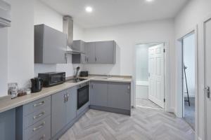a kitchen with white cabinets and a sink and a microwave at Host & Stay - Loftus Apartments in Loftus