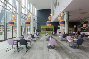 un restaurante con sillas moradas, mesas y ventanas en voco Milan-Fiere, an IHG Hotel, en Milán