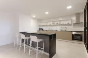 cocina con paredes blancas y encimera con taburetes en Exceptional Apartament Near To Sh Del Sol, en Asunción