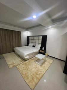 um quarto com uma cama branca e uma mesa em الراحة بلازا للشقق المفروشة em Sharurah