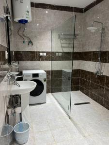 uma casa de banho com um chuveiro, um lavatório e uma máquina de lavar roupa em الراحة بلازا للشقق المفروشة em Sharurah