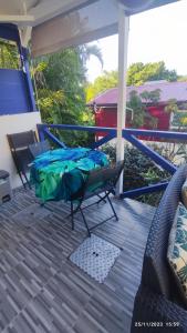 a porch with a bed and chairs on a deck at TI SOLEY Bungalow de charme avec piscine in Bouillante