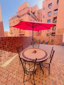 una mesa con una sombrilla roja en el patio en appartement dino, en Marrakech
