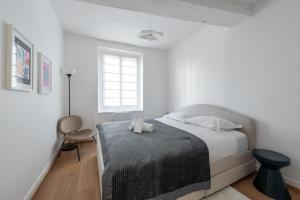 ein weißes Schlafzimmer mit einem Bett und einem Stuhl in der Unterkunft Alma - Charmant apt 2 chambres in Lyon