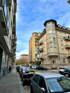 una calle de la ciudad con coches y edificios aparcados en Casa Genovesi - vicino Porta Nuova F.S., en Turín