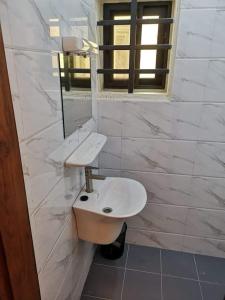 uma casa de banho branca com um lavatório e um espelho em Appartement meublé em Cotonou