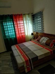 um quarto com janelas coloridas e uma cama em Appartement meublé em Cotonou