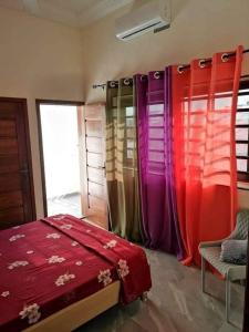 um quarto com cortinas coloridas e uma cama e uma cadeira em Appartement meublé em Cotonou