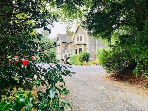 ein großes Haus wird durch die Bäume gesehen in der Unterkunft Ambleside Manor - Vegetarian B&B in Ambleside