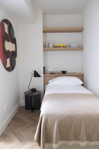 ein Schlafzimmer mit einem Bett und einem Tisch mit einer Lampe in der Unterkunft The Onsider - Penthouse 3 Bedroom Apartment - Paseo de Gracia in Barcelona