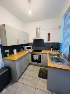 uma cozinha com um lavatório e um fogão forno superior em 4 Bed 4 Bath 6 Guest Lovely home em Stoke on Trent