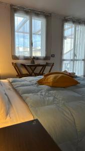 a large bed with a yellow pillow in a room with windows at Appartamento Vittoria in Vittoria