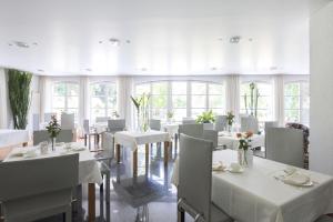 a dining room with white tables and white chairs at ArtVilla am See - offen März bis Ende Oktober in Radolfzell am Bodensee
