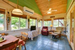 sala de estar con ventilador de techo y ventanas en Warm and Cozy Clayton Cabin Near St Lawrence River!, en Clayton