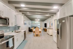 a kitchen with white cabinets and a table with chairs at Bright Jekyll Island Home with Deck Less Than 1 Mi to Beach in Jekyll Island