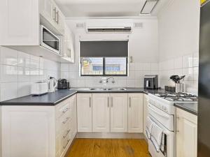 a white kitchen with a sink and a stove at 'The Grange' Coastal Charm near Henley Beach in Adelaide