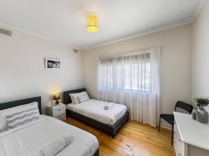 a bedroom with two beds and a window at 'The Grange' Coastal Charm near Henley Beach in Adelaide