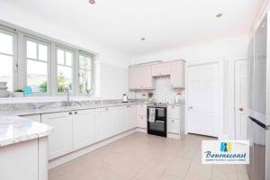 een witte keuken met witte kasten en een zwart apparaat bij BOURNECOAST:LARGE HOME MINUTES FROM BEACH- HB6228 in Bournemouth