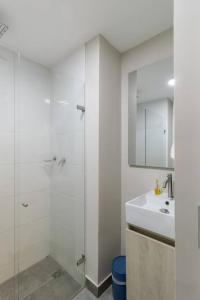 a white bathroom with a shower and a sink at Apartamento Tranvía 210 in Medellín