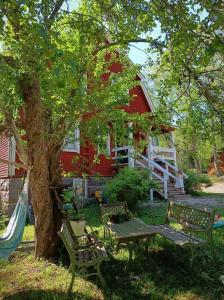 ein rotes Haus mit einem Baum, Stühlen und einer Schaukel in der Unterkunft Tunnelmallinen kaksio hirsitalossa 