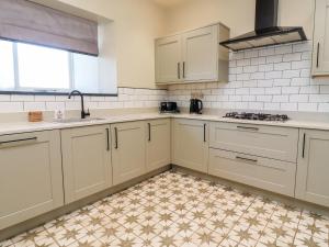 a kitchen with white cabinets and a tile floor at Rathmell in Skipton