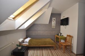 a bedroom with a bed and a desk in a attic at Pokoje Zygmuntowska in Nowy Sącz