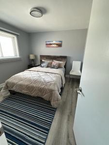 Spotless 2 Bedroom Suite in Winnipeg في وينيبيغ: غرفة نوم بسرير وباب بساط