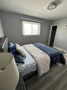Spotless 2 Bedroom Suite in Winnipeg في وينيبيغ: غرفة نوم بسرير وملاءات زرقاء ونافذة