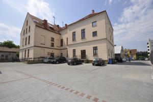 un gran edificio con coches estacionados en un estacionamiento en Pokoje Zygmuntowska, en Nowy Sącz