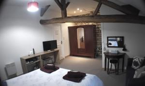 a bedroom with a bed and a table and a television at Le Vieux Logis in Montreuil-Bellay