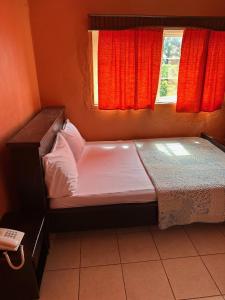 Cama pequeña en habitación con ventana en STONE CASTLE HOTEL, en Freetown