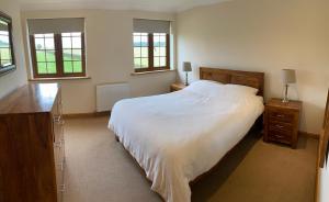 une chambre avec un grand lit blanc et deux fenêtres dans l'établissement Red House Farm Cottages, à Beverley