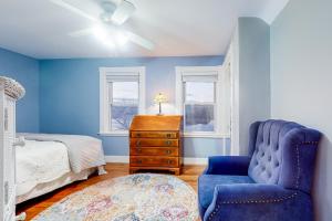 a blue bedroom with a bed and a blue chair at Goat Hill Cottage in Beverly