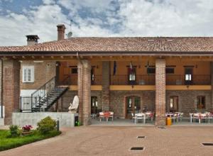 a large brick building with a balcony and tables at Antica Cascina B&B in Borghetto Lodigiano