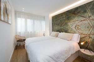 - une chambre dotée d'un grand lit blanc et d'une peinture murale dans l'établissement San Jerónimo Catedral 2BR, à Grenade