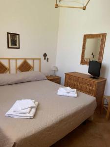 a bedroom with a bed and a mirror and a television at Villetta tre delfini in Custonaci +18 photos