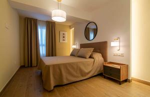 Un dormitorio con una cama grande y un espejo. en Apartamentos 1 Abril, en Málaga
