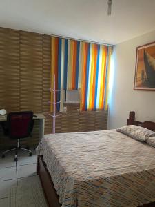 um quarto com uma cama, uma secretária e uma janela em EDIFÍCIO METROPOLE ONDINA em Salvador