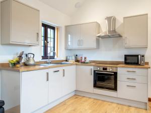 a kitchen with white cabinets and a sink and a microwave at 2 bed in Bath 72836 in Chew Magna